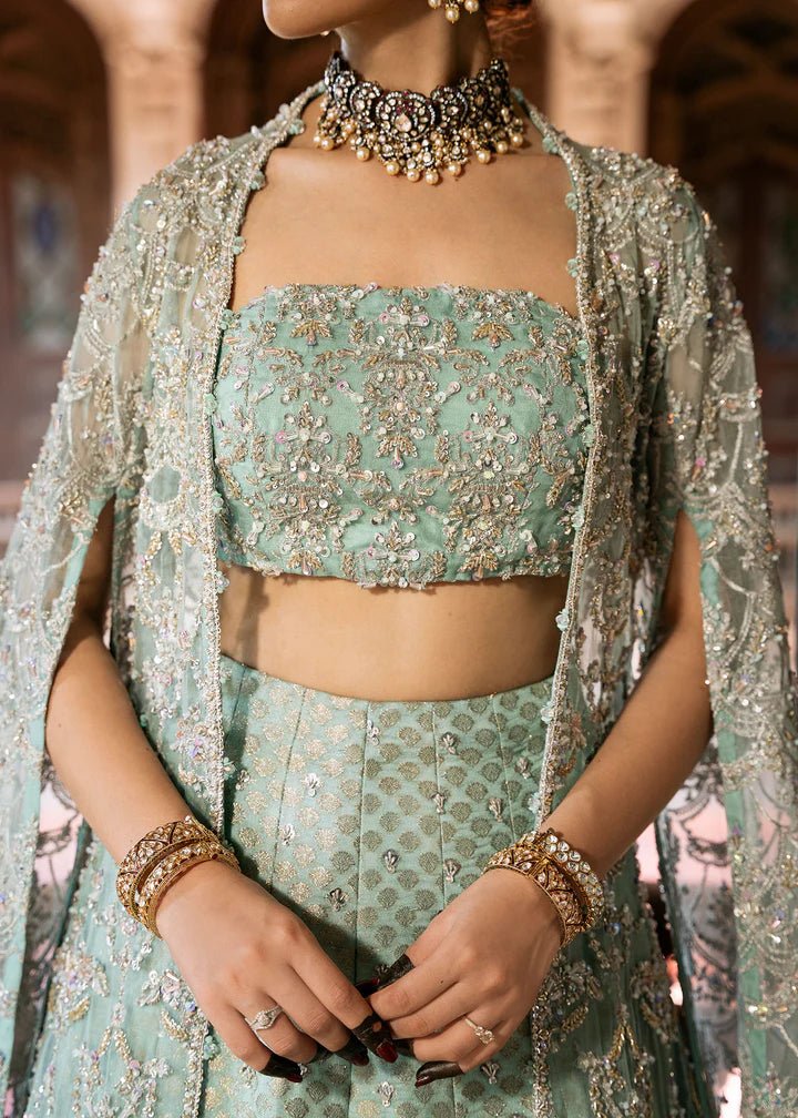 Model wearing a pastel green Shaqfaq dress from Kanwal Malik's Sajni II Formal Collection, featuring intricate embroidery and a matching cape. Pakistani wedding clothes available online in the UK.