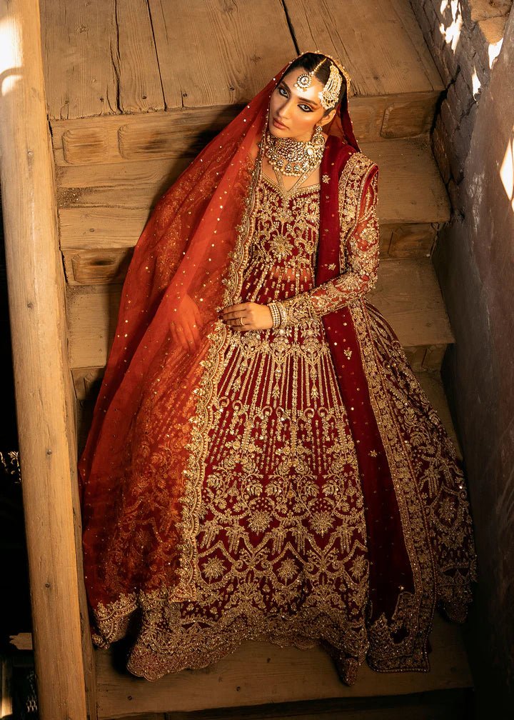 Model wearing a deep red Shirin lehenga from Kanwal Malik's Sajni II Formal Collection, intricately adorned with gold embroidery and paired with a matching dupatta. Pakistani wedding clothes available online in the UK.