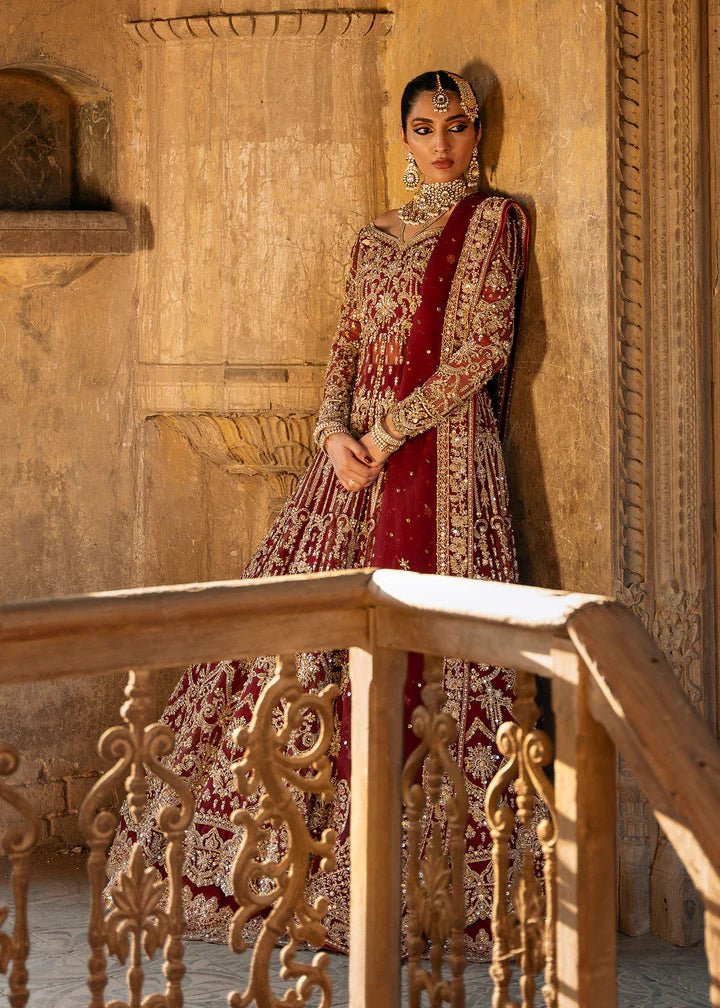 Model wearing a deep red Shirin lehenga from Kanwal Malik's Sajni II Formal Collection, intricately adorned with gold embroidery and paired with a matching dupatta. Pakistani wedding clothes available online in the UK.