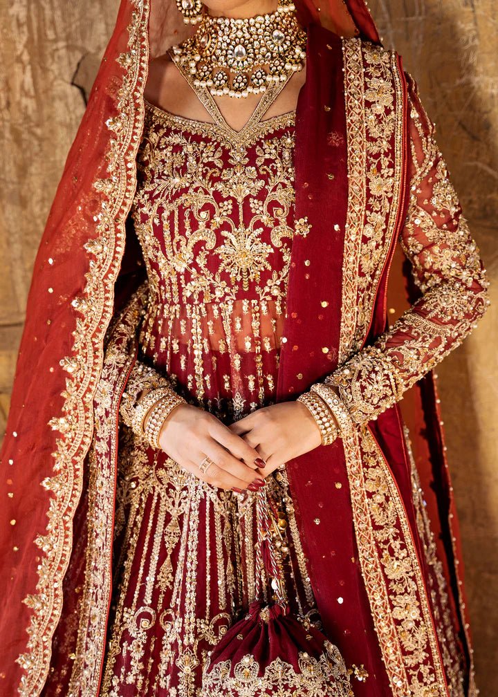 Model wearing a deep red Shirin lehenga from Kanwal Malik's Sajni II Formal Collection, intricately adorned with gold embroidery and paired with a matching dupatta. Pakistani wedding clothes available online in the UK.