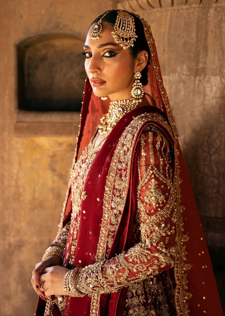 Model wearing a deep red Shirin lehenga from Kanwal Malik's Sajni II Formal Collection, intricately adorned with gold embroidery and paired with a matching dupatta. Pakistani wedding clothes available online in the UK.