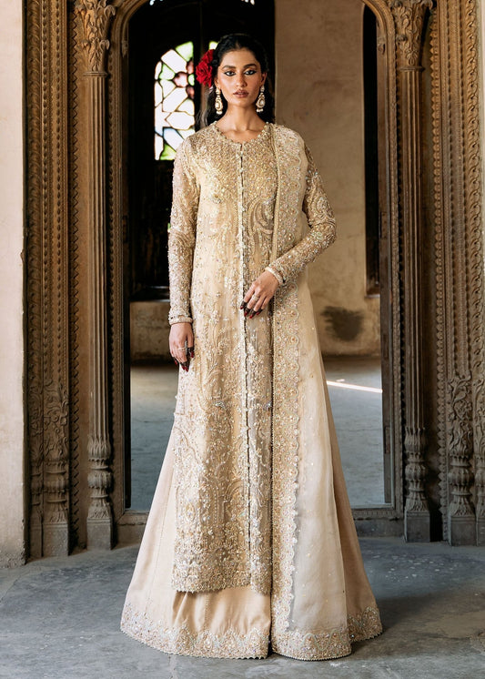 Model wearing an ivory - colored Zarnab dress from Kanwal Malik's Sajni II Formal Collection, adorned with intricate embellishments. Pakistani wedding clothes available online in the UK.