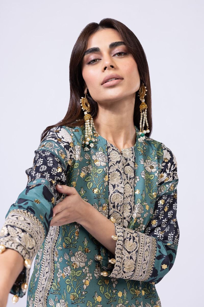 Model wearing Khaadi EST24563A teal dress with intricate prints and embroidered details. Shop Pakistani clothes online in the UK now.