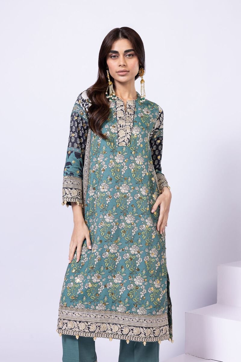 Model wearing Khaadi EST24563A teal dress with intricate prints and embroidered details. Shop Pakistani clothes online in the UK now.