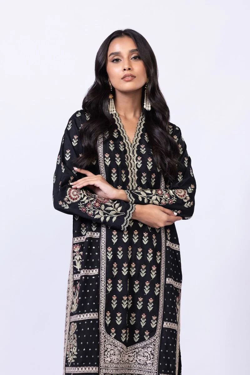 Model wearing Khaadi EST24610B black dress with intricate red and gold prints. Shop Pakistani clothes online in the UK now.