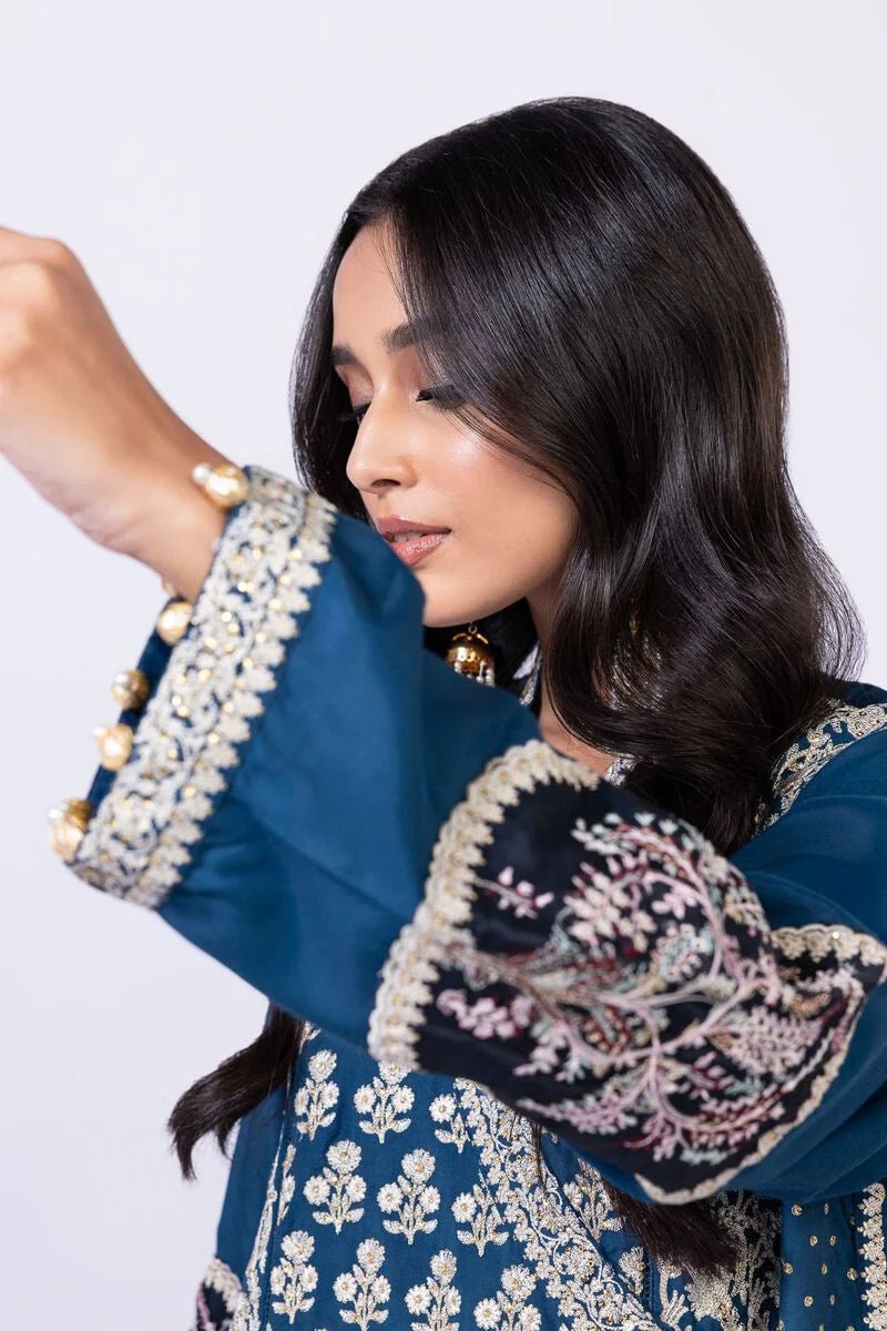 Model wearing Khaadi EST24615A teal dress with intricate embroidery and tassel details. Shop Pakistani clothes online in the UK now.