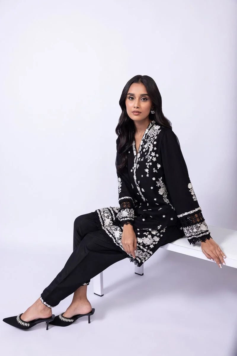 Model wearing Khaadi EST24633B black dress with elegant white embroidery and lace details. Shop Pakistani clothes online in the UK now.