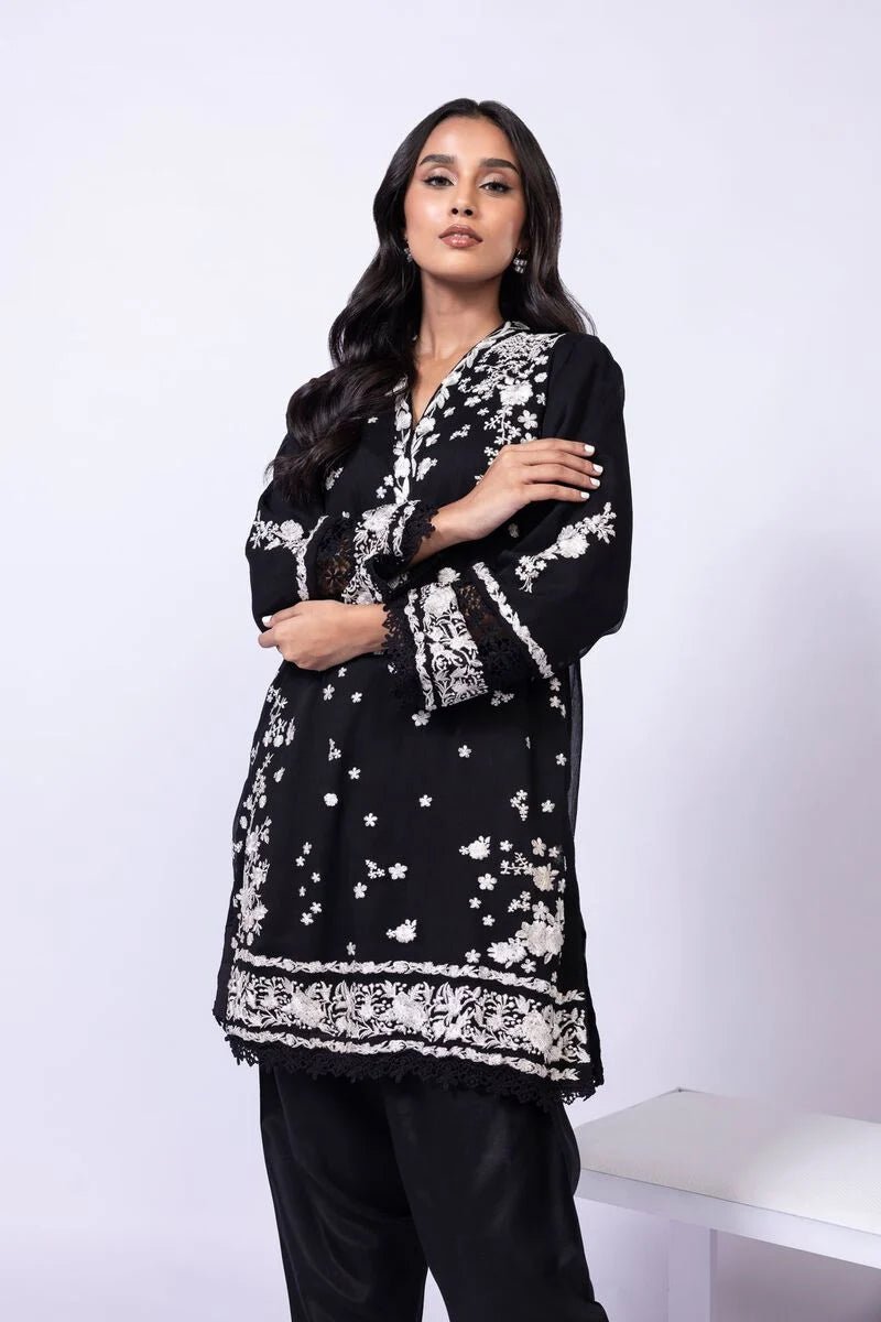 Model wearing Khaadi EST24633B black dress with elegant white embroidery and lace details. Shop Pakistani clothes online in the UK now.