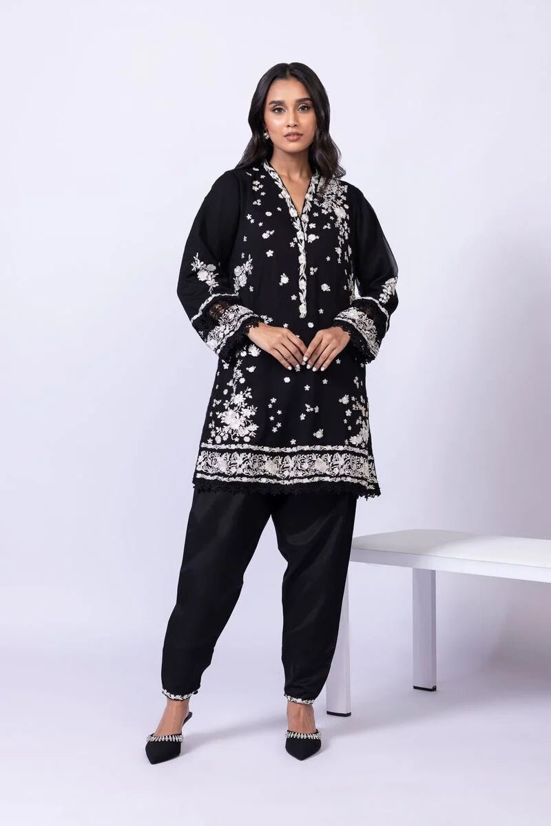 Model wearing Khaadi EST24633B black dress with elegant white embroidery and lace details. Shop Pakistani clothes online in the UK now.