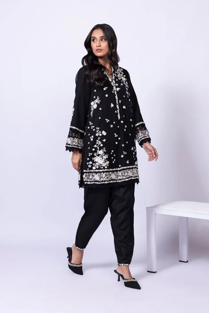 Model wearing Khaadi EST24633B black dress with elegant white embroidery and lace details. Shop Pakistani clothes online in the UK now.