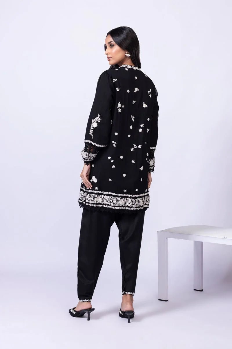 Model wearing Khaadi EST24633B black dress with elegant white embroidery and lace details. Shop Pakistani clothes online in the UK now.