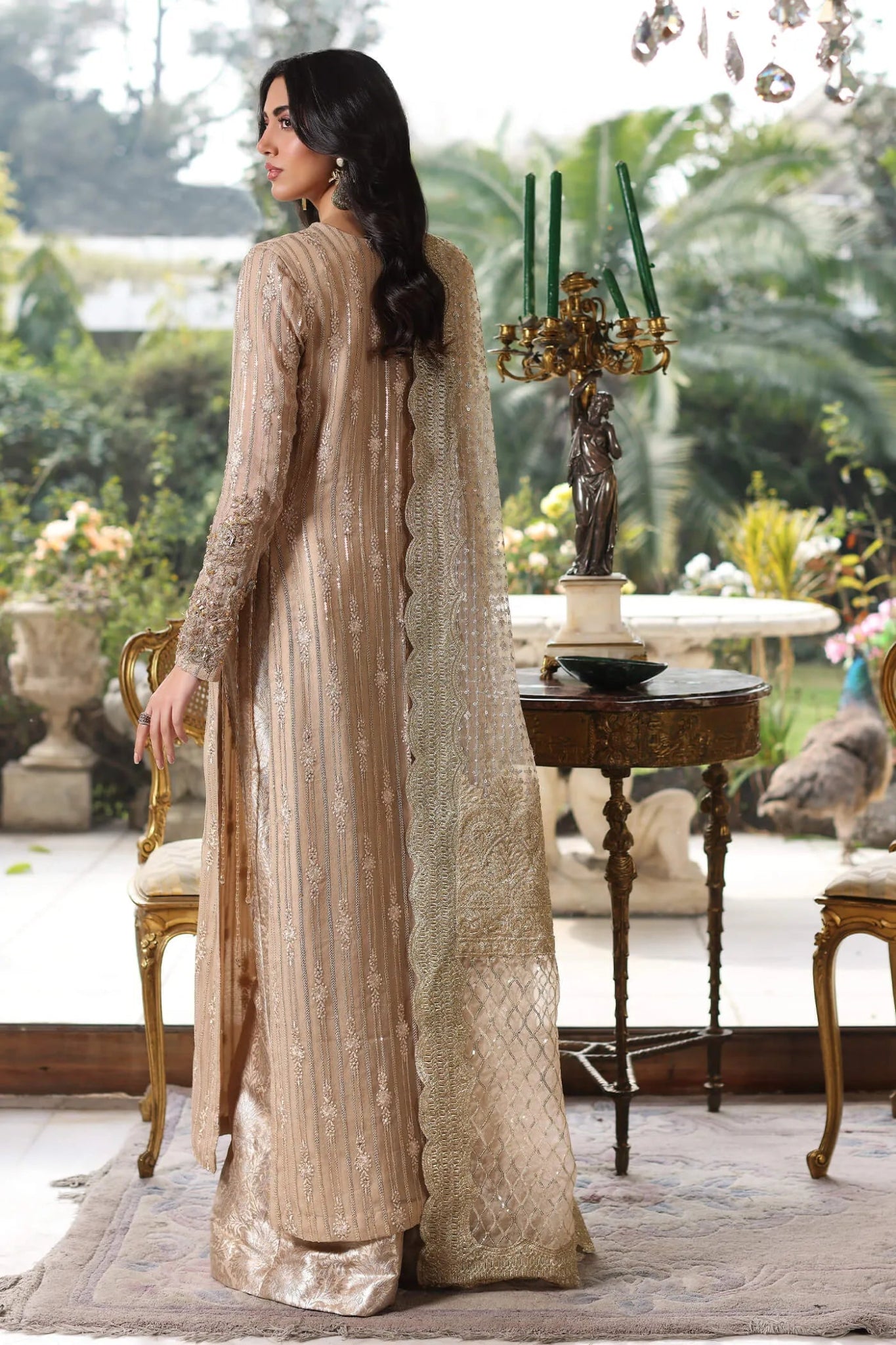 Model wearing a gold ENCHANTÉ dress from Musferah Saad's ENCHANTE Eid collection '24, showcasing Pakistani clothes online in the UK.