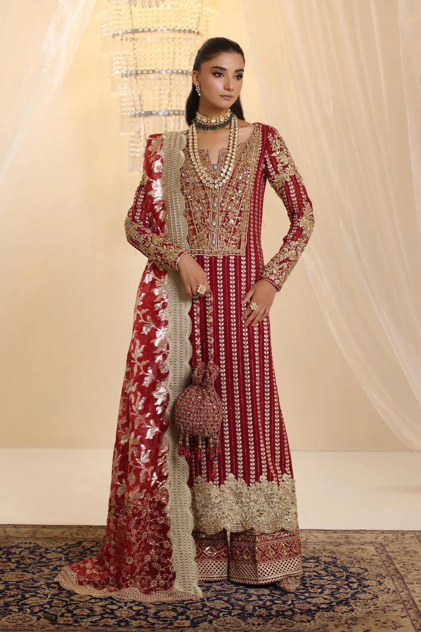 Model wearing Musferah Saad Crimson Royale dress in deep red and gold from the Ethereal Dream Formals collection, perfect for Pakistani wedding clothes online in the UK.