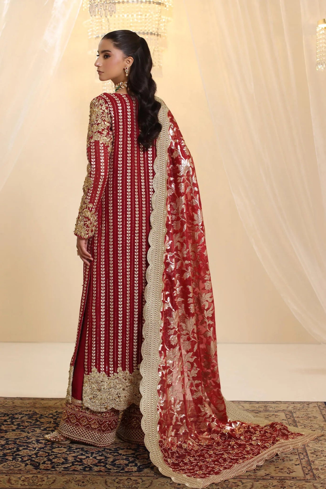 Model wearing Musferah Saad Crimson Royale dress in deep red and gold from the Ethereal Dream Formals collection, perfect for Pakistani wedding clothes online in the UK.