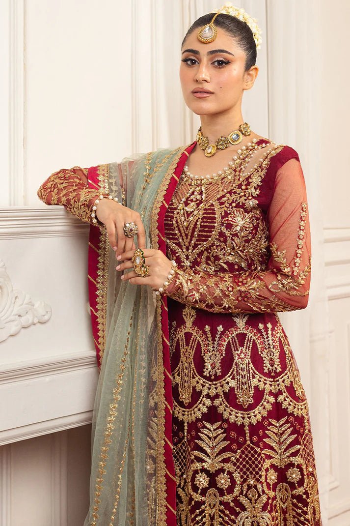 Model wearing a deep red and gold intricately embroidered Asian wedding formal dress, "Scarlet," from Mushq. Pakistani wedding clothes online in the UK.