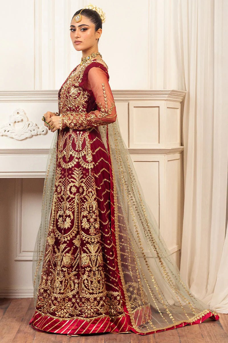 Model wearing a deep red and gold intricately embroidered Asian wedding formal dress, "Scarlet," from Mushq. Pakistani wedding clothes online in the UK.