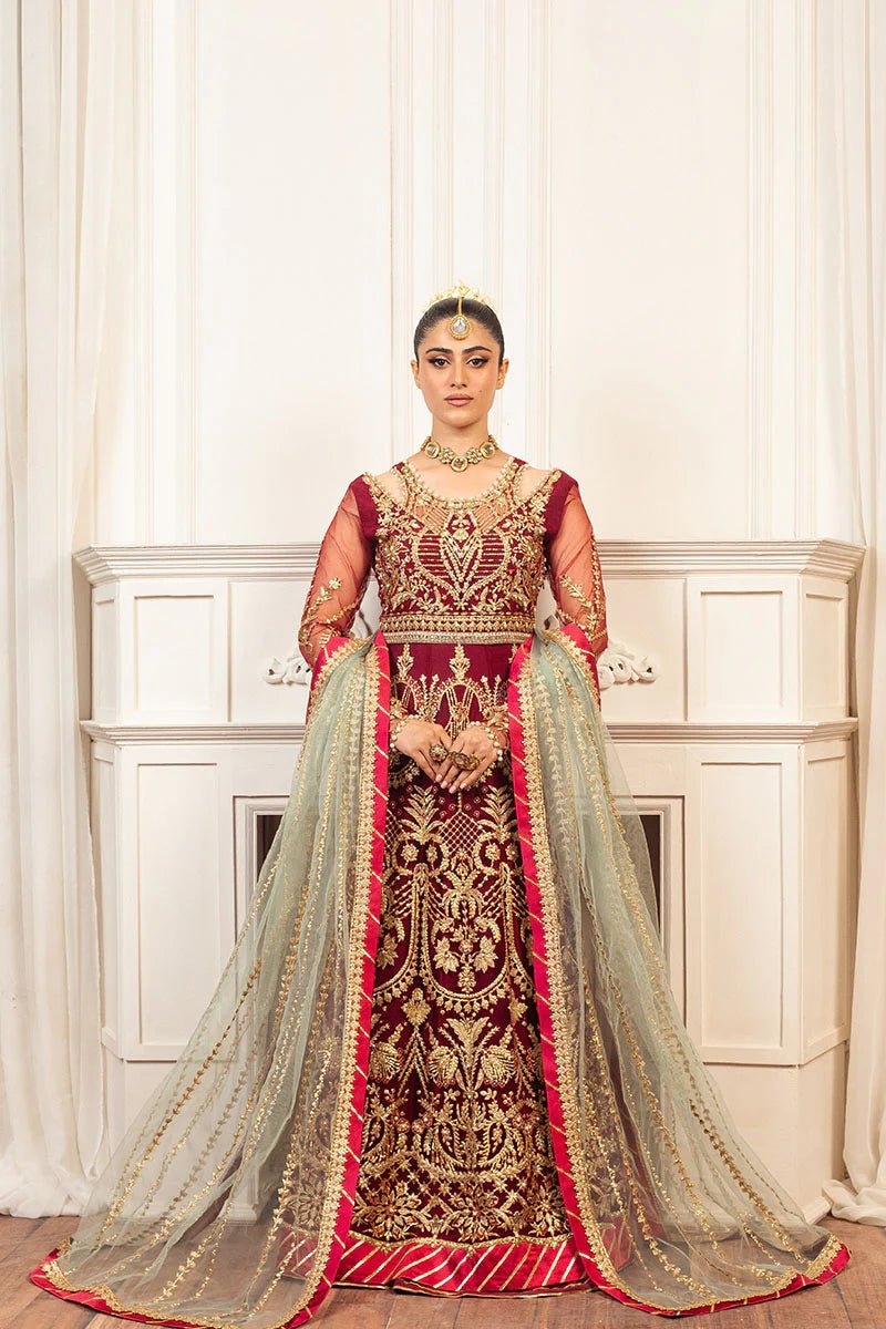 Model wearing a deep red and gold intricately embroidered Asian wedding formal dress, "Scarlet," from Mushq. Pakistani wedding clothes online in the UK.