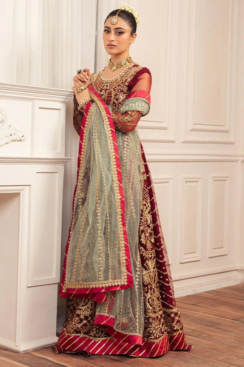 Model wearing a deep red and gold intricately embroidered Asian wedding formal dress, "Scarlet," from Mushq. Pakistani wedding clothes online in the UK.