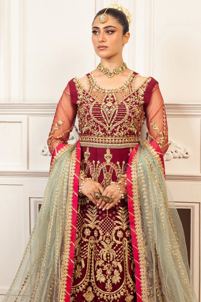 Model wearing a deep red and gold intricately embroidered Asian wedding formal dress, "Scarlet," from Mushq. Pakistani wedding clothes online in the UK.