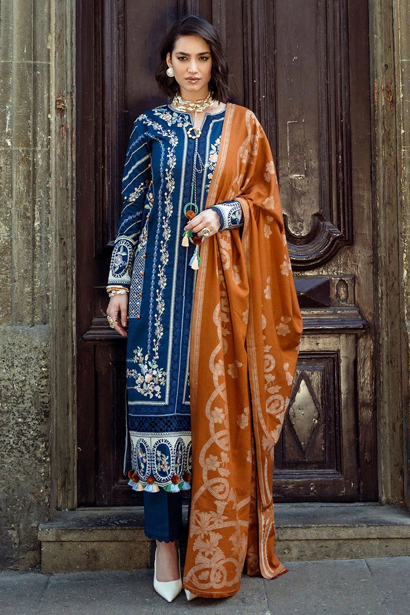 Model wearing Mushq Broadway A Walk to Remember Sweet Surrender, a blue dress with intricate embroidery and an orange shawl, perfect for winter casual wear. Available for Pakistani clothes online in the UK.