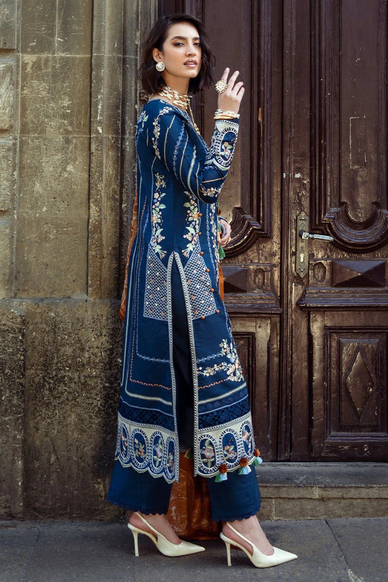 Model wearing Mushq Broadway A Walk to Remember Sweet Surrender, a blue dress with intricate embroidery and an orange shawl, perfect for winter casual wear. Available for Pakistani clothes online in the UK.