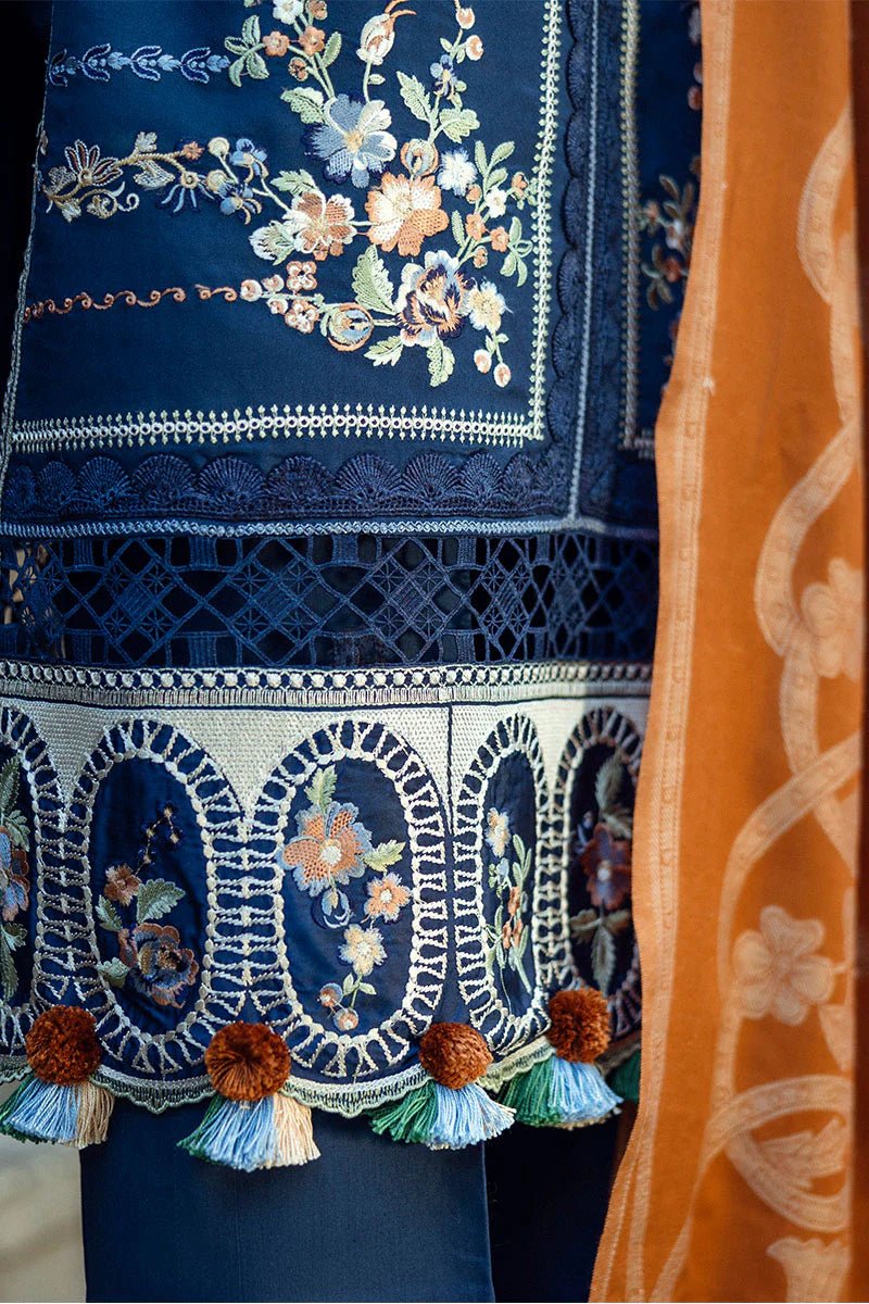 Model wearing Mushq Broadway A Walk to Remember Sweet Surrender, a blue dress with intricate embroidery and an orange shawl, perfect for winter casual wear. Available for Pakistani clothes online in the UK.