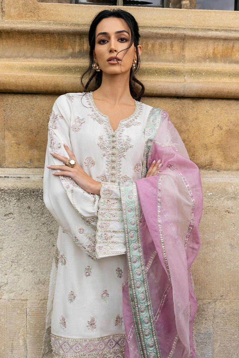 Model wearing a white Luminous Lace dress with intricate embroidery and a lavender dupatta from Mushq, perfect for weddings. Available for Pakistani clothes online in the UK.