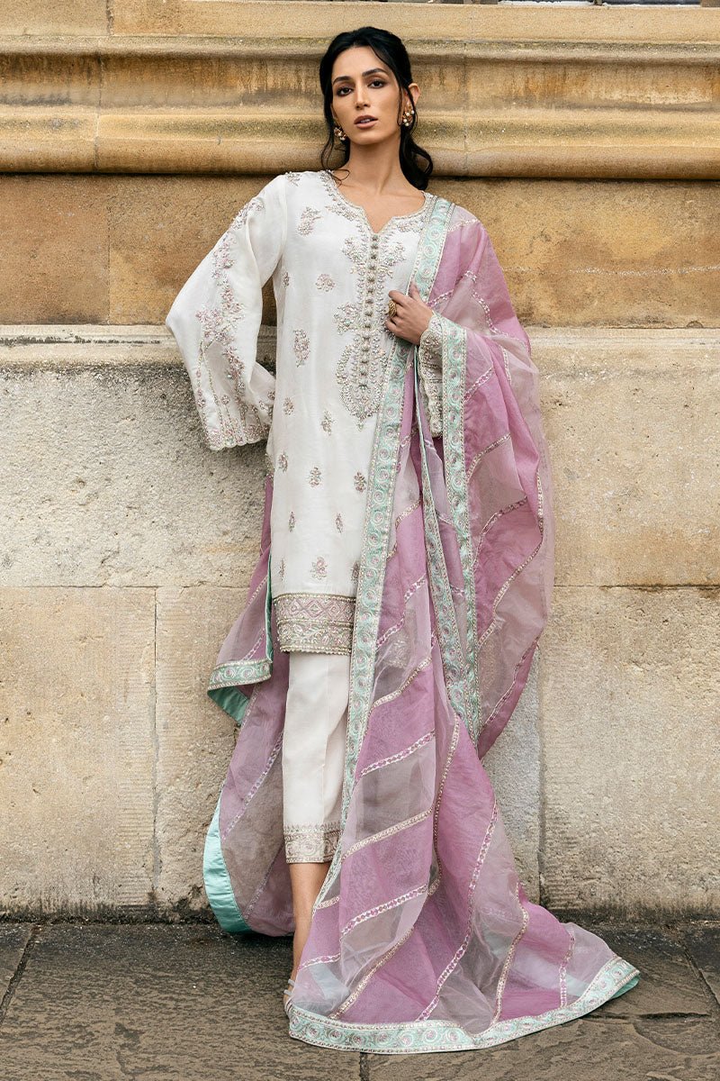 Model wearing a white Luminous Lace dress with intricate embroidery and a lavender dupatta from Mushq, perfect for weddings. Available for Pakistani clothes online in the UK.