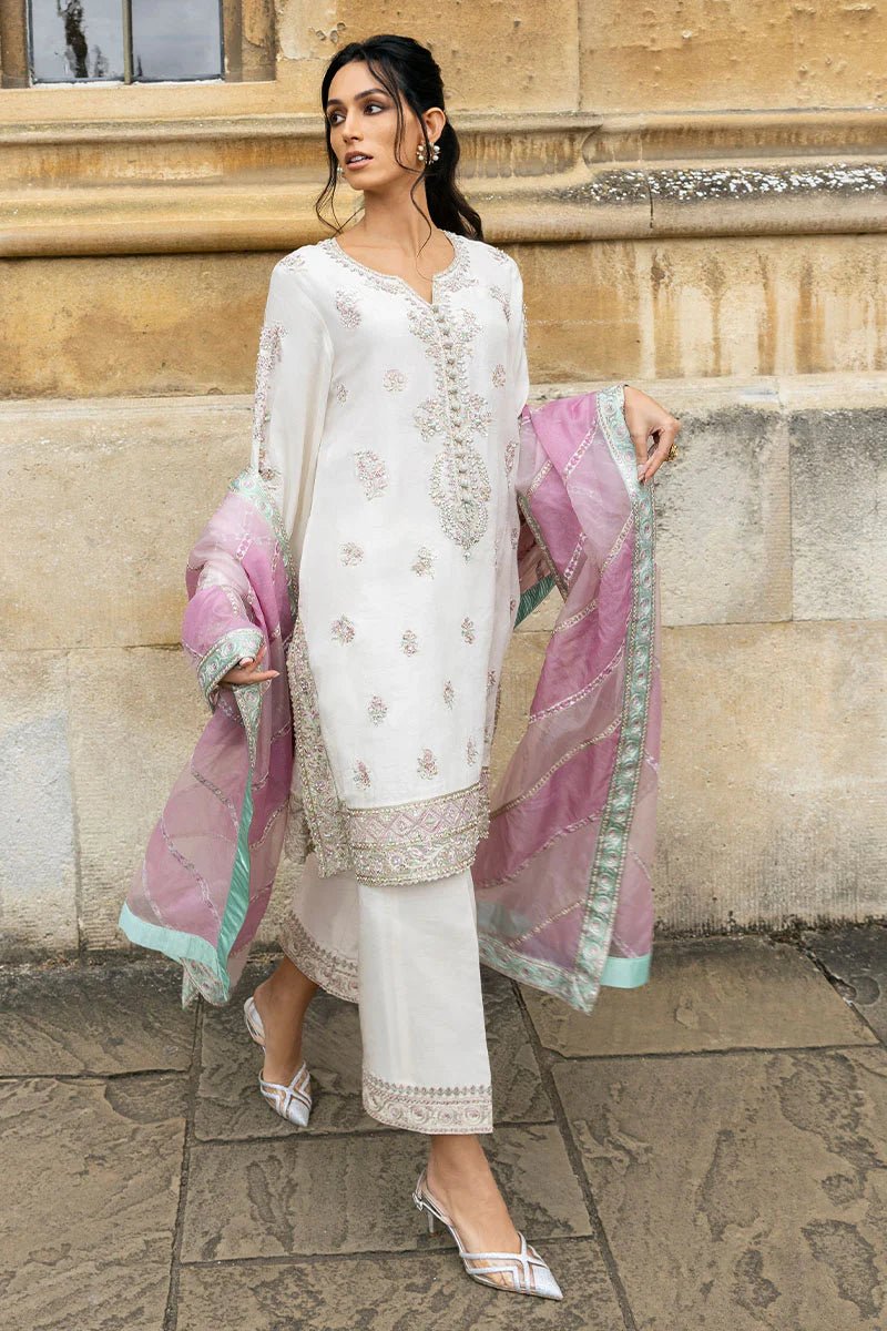 Model wearing a white Luminous Lace dress with intricate embroidery and a lavender dupatta from Mushq, perfect for weddings. Available for Pakistani clothes online in the UK.