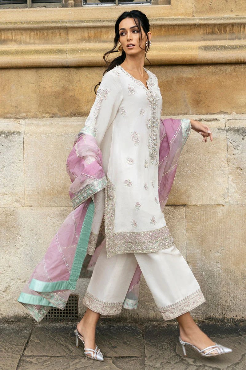 Model wearing a white Luminous Lace dress with intricate embroidery and a lavender dupatta from Mushq, perfect for weddings. Available for Pakistani clothes online in the UK.