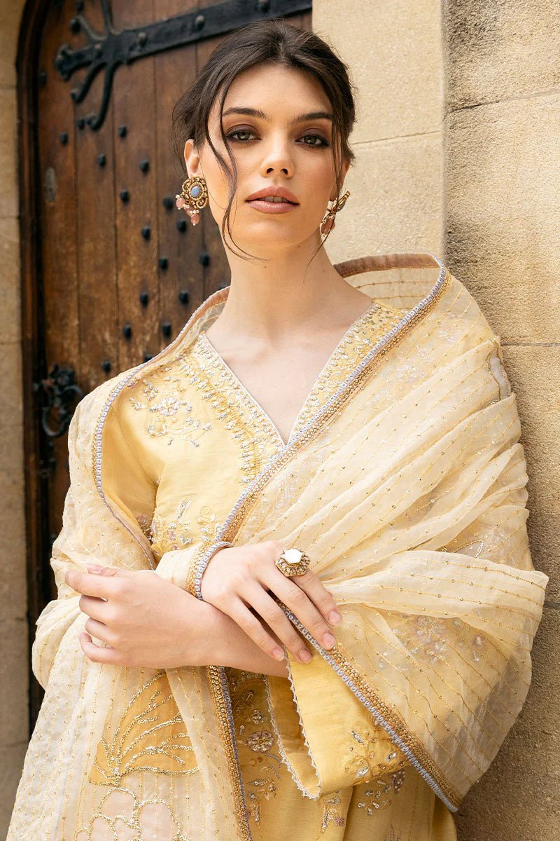 Model wearing a yellow Lyravia dress from Mushq, featuring intricate floral embroidery. Keywords: Mushq, Pakistani clothes online in UK, wedding clothes.