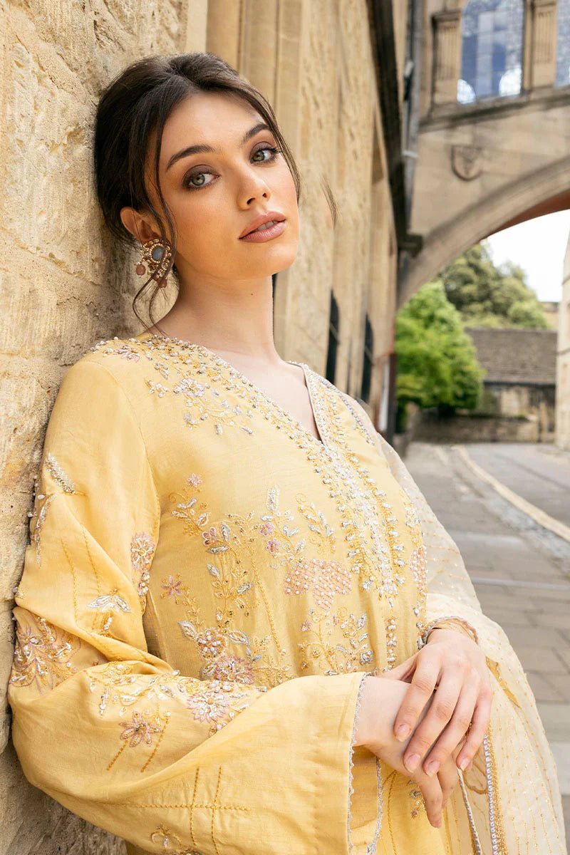 Model wearing a yellow Lyravia dress from Mushq, featuring intricate floral embroidery. Keywords: Mushq, Pakistani clothes online in UK, wedding clothes.