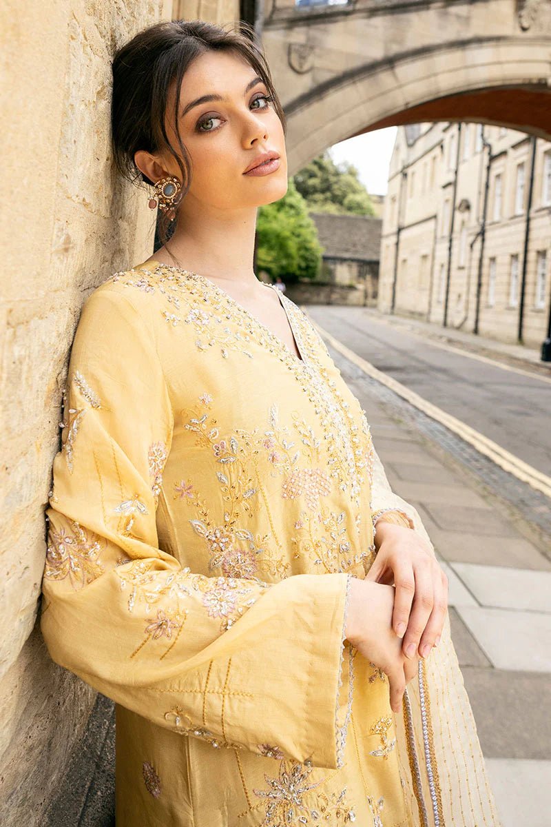 Model wearing a yellow Lyravia dress from Mushq, featuring intricate floral embroidery. Keywords: Mushq, Pakistani clothes online in UK, wedding clothes.