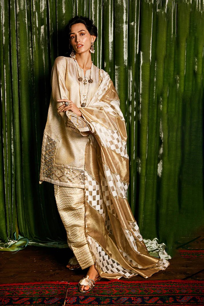 Model wearing a golden Basanti outfit from Mushq with intricate gota detailing, showcasing Pakistani designer clothes online in the UK, perfect for weddings.