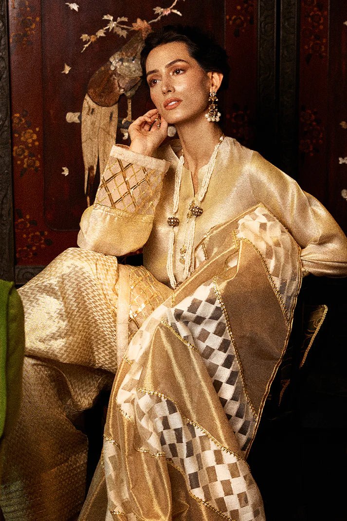 Model wearing a golden Basanti outfit from Mushq with intricate gota detailing, showcasing Pakistani designer clothes online in the UK, perfect for weddings.