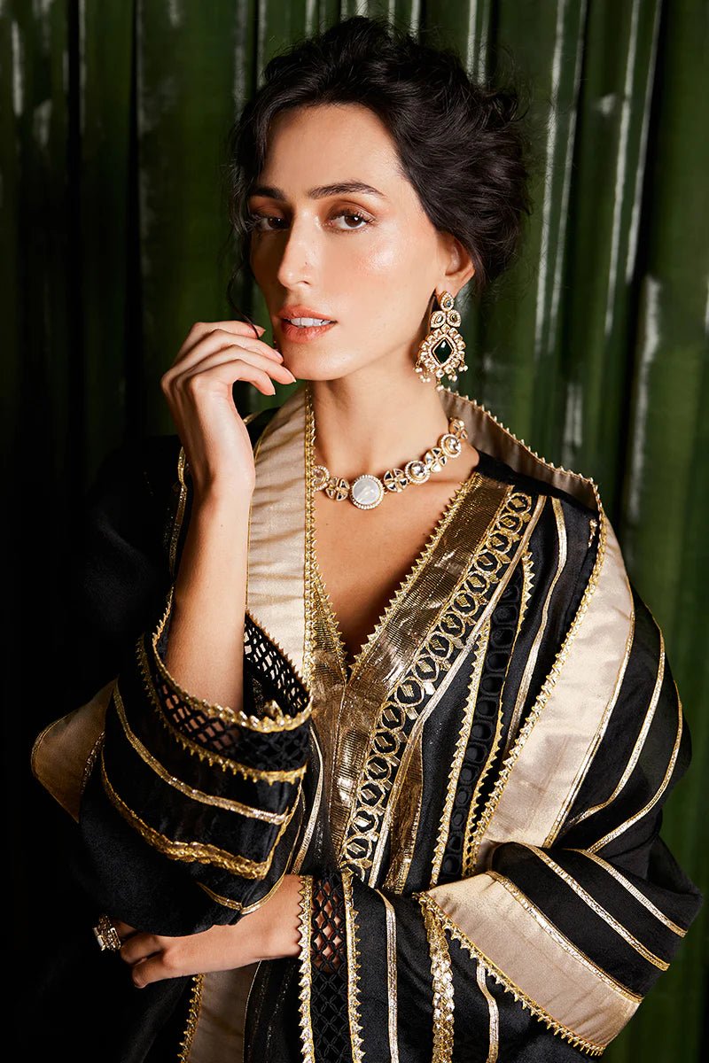 Model wearing a striking black and gold Koyal dress from Mushq with intricate gota detailing, ideal for Pakistani weddings, available online in the UK.