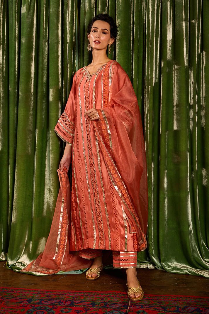 Model wearing a vibrant orange Rajputani Rani outfit from Mushq with intricate gota work, ideal for Pakistani weddings, available online in the UK.