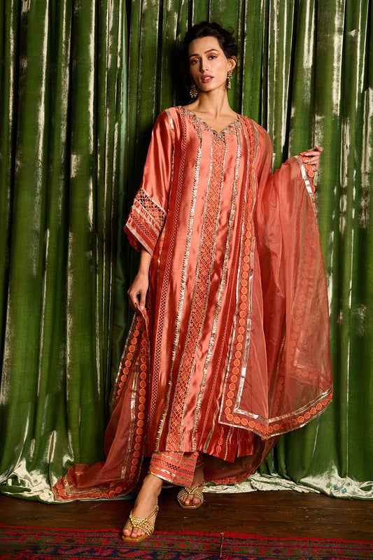 Model wearing a vibrant orange Rajputani Rani outfit from Mushq with intricate gota work, ideal for Pakistani weddings, available online in the UK.