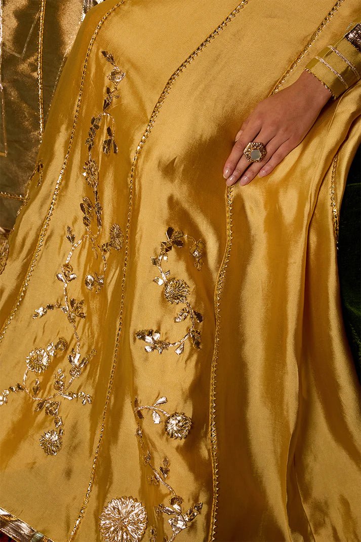 Model wearing a golden Suraj Mukhi lehenga from Mushq, adorned with intricate gota work, perfect for weddings, showcasing Pakistani designer clothes online in the UK.