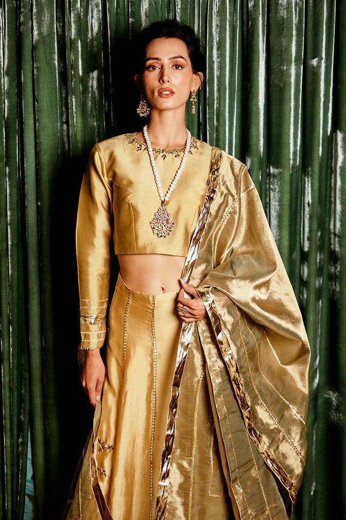 Model wearing a golden Suraj Mukhi lehenga from Mushq, adorned with intricate gota work, perfect for weddings, showcasing Pakistani designer clothes online in the UK.