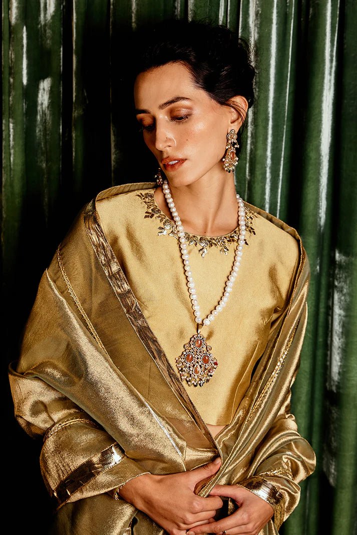 Model wearing a golden Suraj Mukhi lehenga from Mushq, adorned with intricate gota work, perfect for weddings, showcasing Pakistani designer clothes online in the UK.