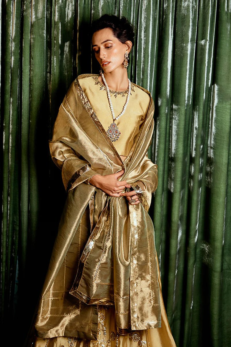 Model wearing a golden Suraj Mukhi lehenga from Mushq, adorned with intricate gota work, perfect for weddings, showcasing Pakistani designer clothes online in the UK.