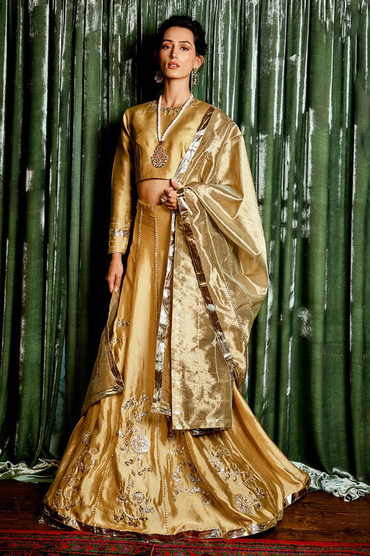 Model wearing a golden Suraj Mukhi lehenga from Mushq, adorned with intricate gota work, perfect for weddings, showcasing Pakistani designer clothes online in the UK.