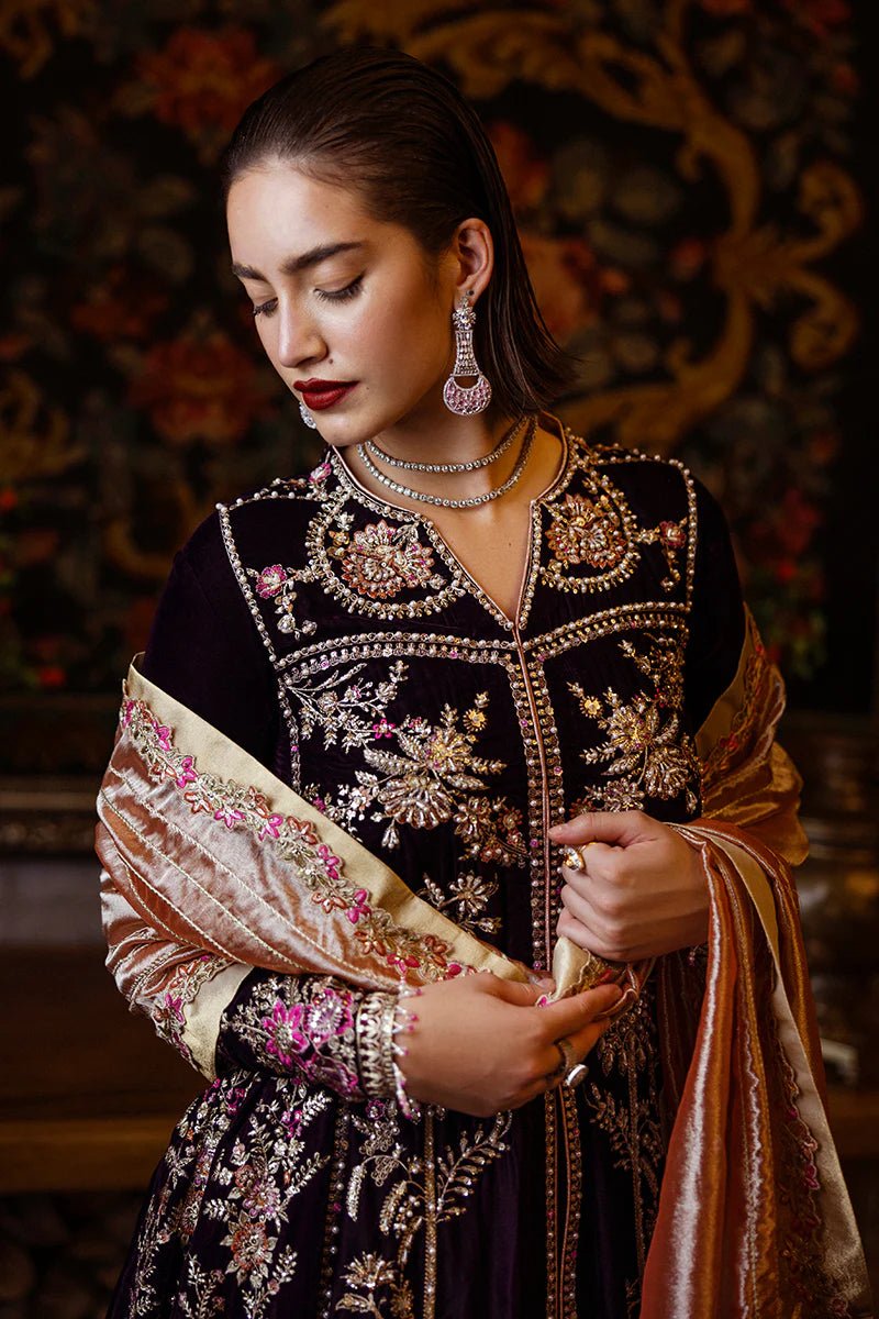 Model wearing Mushq DEJA VU - VELVET '24 Chasing Reflections, a deep purple velvet gown with intricate gold and silver embroidery, paired with a luxurious golden shawl. Perfect for winter weddings, available for Pakistani clothes online in the UK.