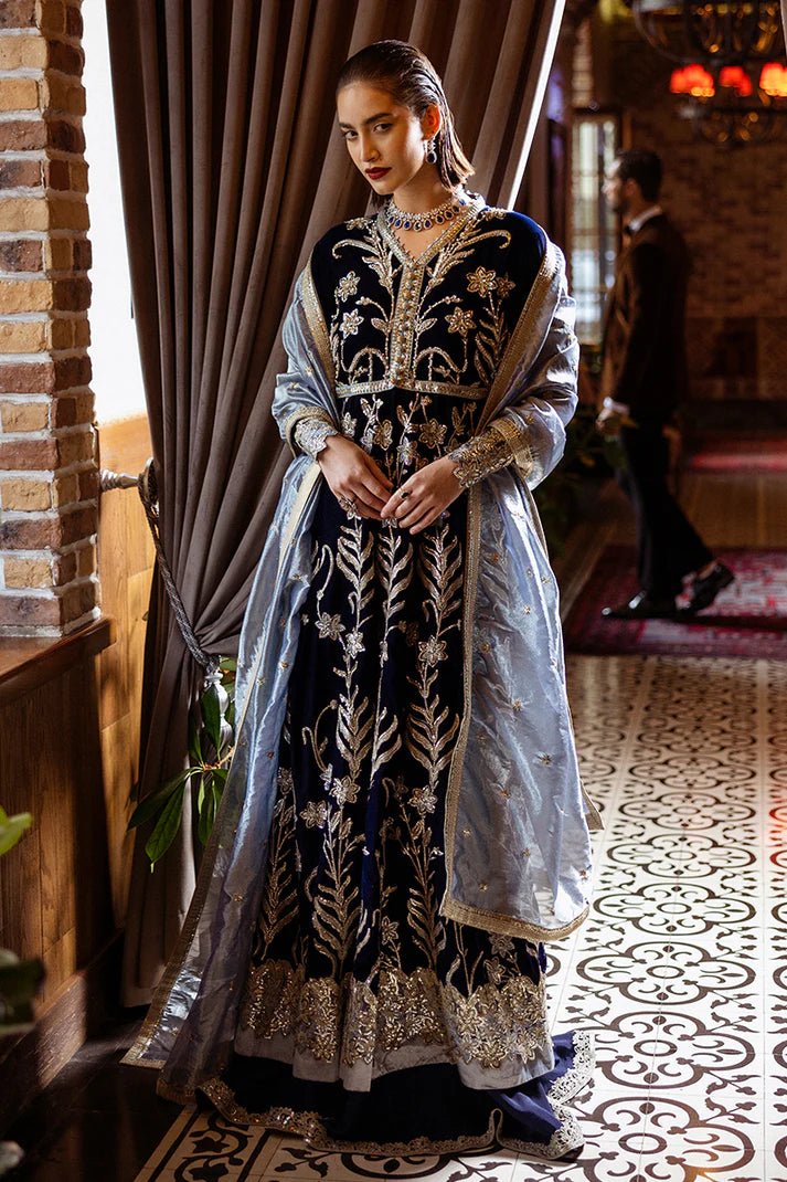 Model wearing Mushq DEJA VU - VELVET '24 Timeless Mirage, a rich navy velvet gown with intricate gold embroidery and silver accents, paired with a luxurious silver shawl. Perfect for winter weddings, available for Pakistani clothes online in the UK.