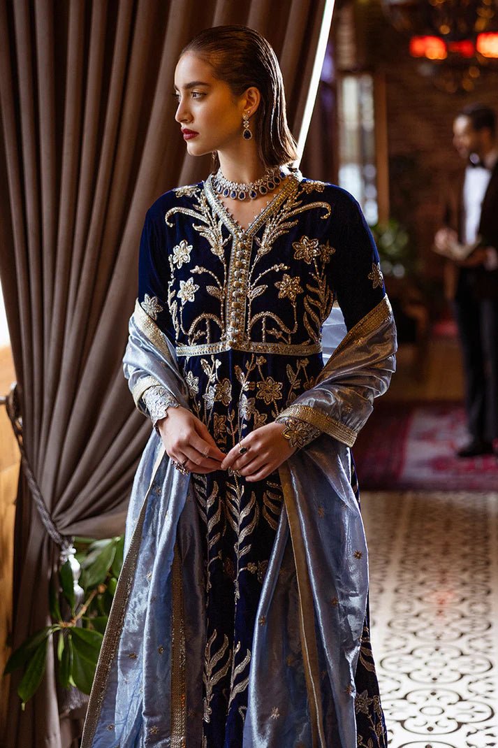 Model wearing Mushq DEJA VU - VELVET '24 Timeless Mirage, a rich navy velvet gown with intricate gold embroidery and silver accents, paired with a luxurious silver shawl. Perfect for winter weddings, available for Pakistani clothes online in the UK.