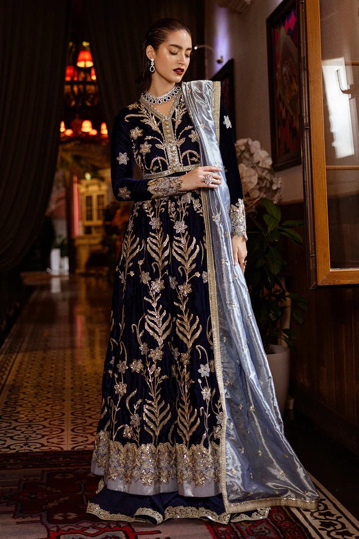 Model wearing Mushq DEJA VU - VELVET '24 Timeless Mirage, a rich navy velvet gown with intricate gold embroidery and silver accents, paired with a luxurious silver shawl. Perfect for winter weddings, available for Pakistani clothes online in the UK.