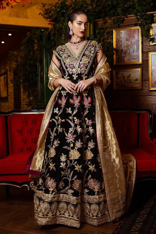 Model wearing Mushq DEJA VU - VELVET '24 Whispers of Yesterday, a black velvet gown with intricate gold and red floral embroidery, styled with a luxurious golden shawl. Ideal for winter weddings, available for Pakistani clothes online in the UK.