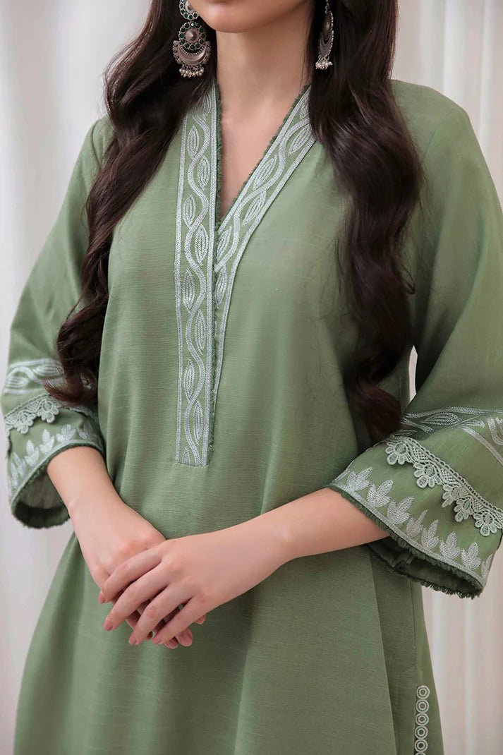 Model wearing Mushq Wisteria Winter Basic Pret '24 Alpine Aura, a sage green dress with floral embroidery, ideal for winter casual wear. Available for Pakistani clothes online in the UK.