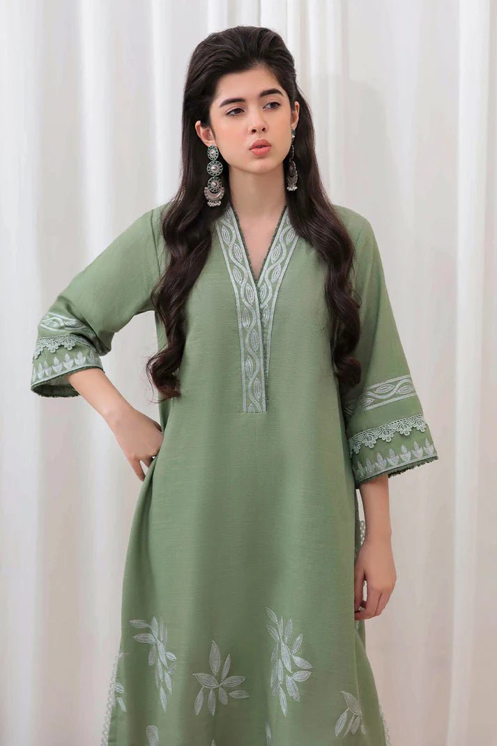 Model wearing Mushq Wisteria Winter Basic Pret '24 Alpine Aura, a sage green dress with floral embroidery, ideal for winter casual wear. Available for Pakistani clothes online in the UK.